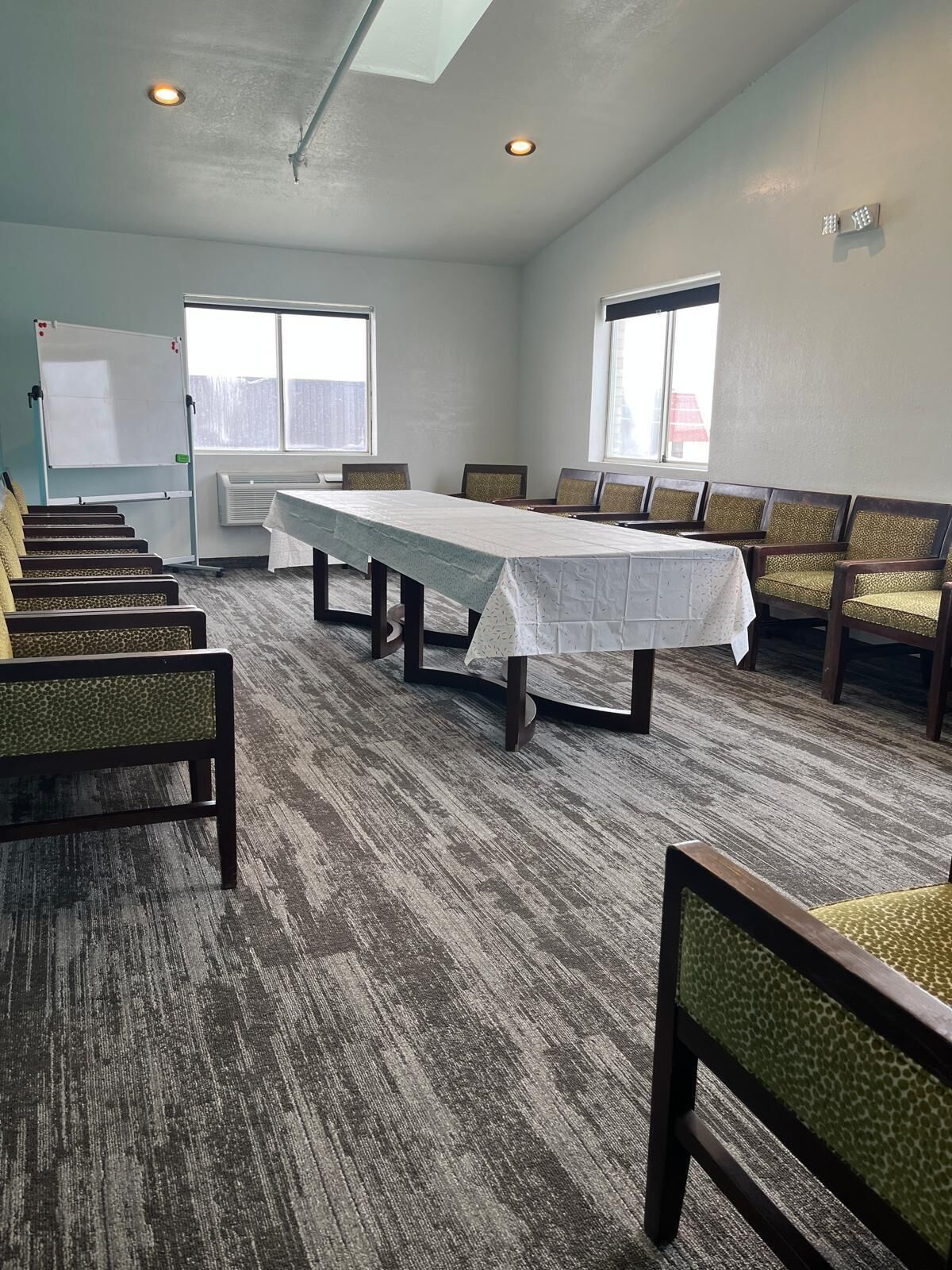 A conference room with a long table, chairs, a whiteboard, and windows.