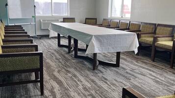 A conference room with a long table, chairs, a whiteboard, and windows.