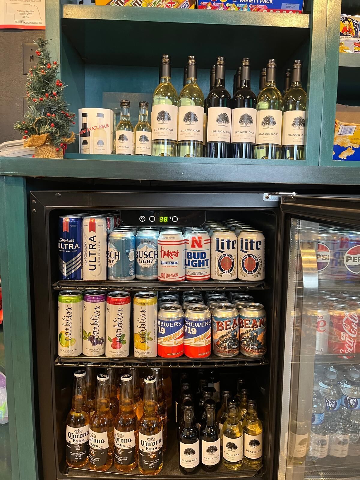 A refrigerated display case with various alcoholic beverages including wine, beer, and mixed drinks.
