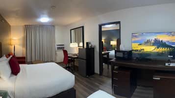 A hotel room with a bed, desk, chair, television, and a large window with curtains.