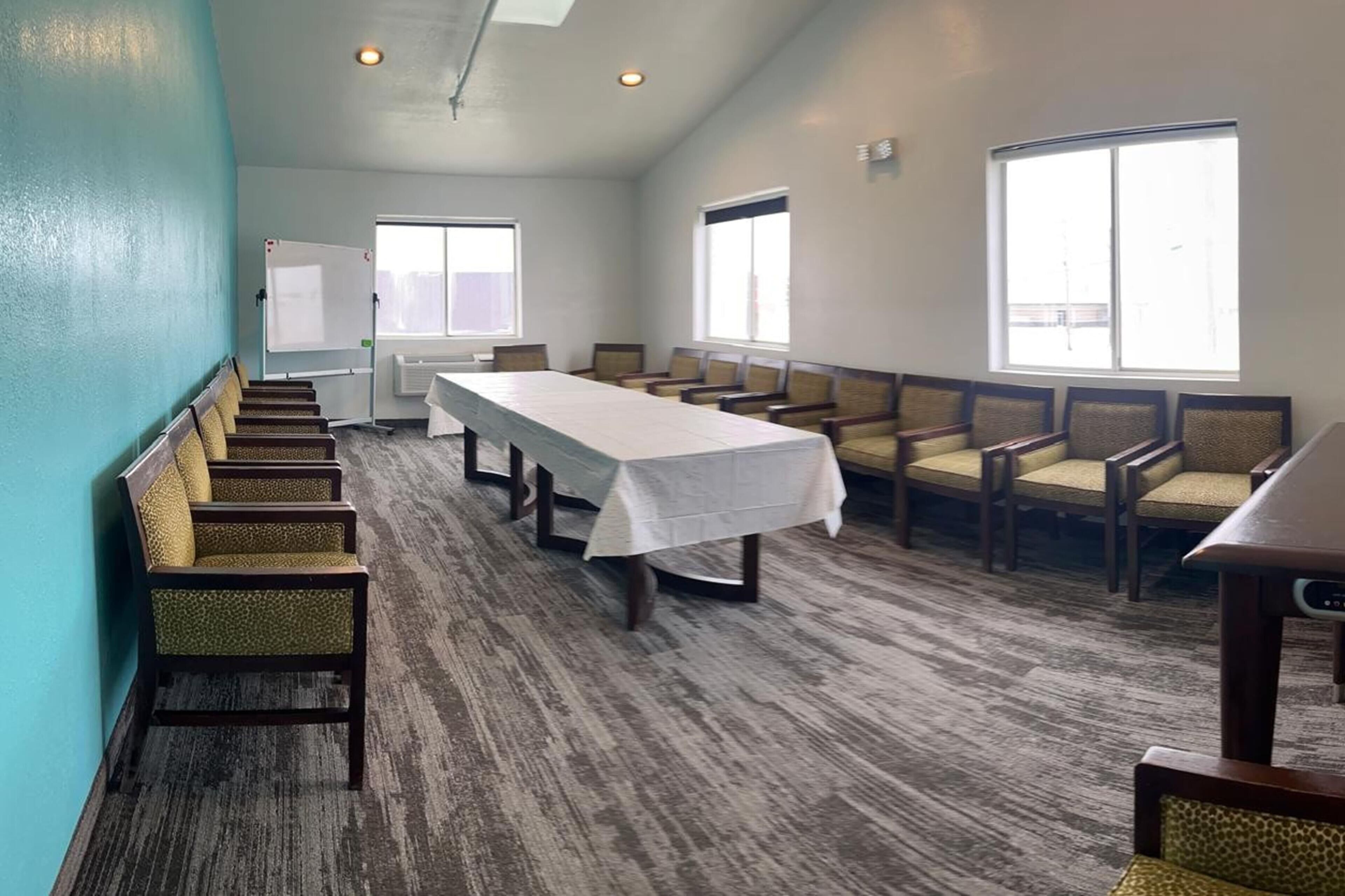 A conference room with a long table, chairs, and large windows.