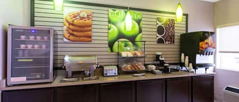 A self-service breakfast station with a coffee machine, toaster, and various pastries.
