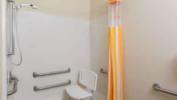 Une salle de bain équipée d’une douche, de barres d’appui, d’une chaise blanche et d’un rideau.