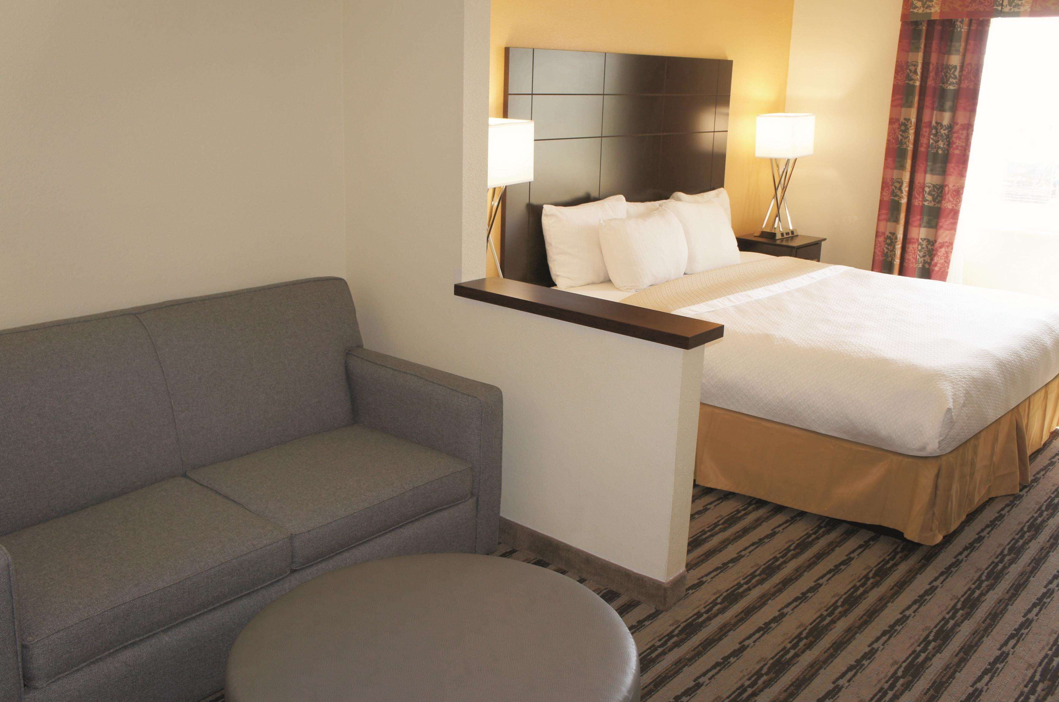 Een hotelkamer met een bed, een slaapbank, een klein rond tafeltje en twee bedlampen.