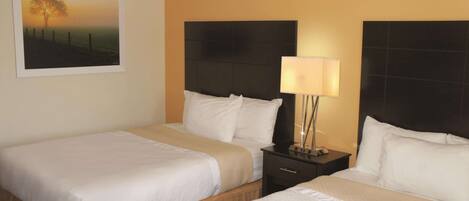 A hotel room with two beds, a nightstand with a lamp, and a framed picture on the wall.