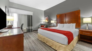Hotelkamer met een groot bed, een bureau, een stoel, een nachtkastje en een televisie.