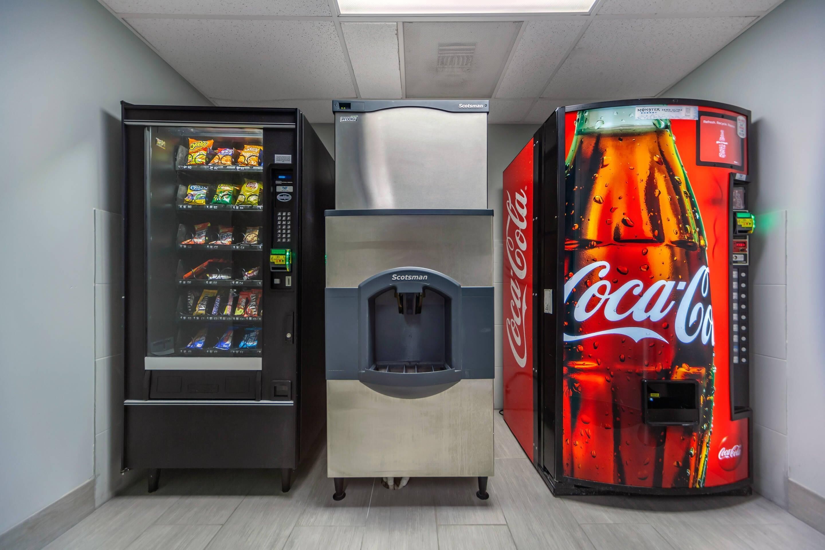 Zona de máquinas expendedoras con una máquina de Coca-Cola y otra de aperitivos.