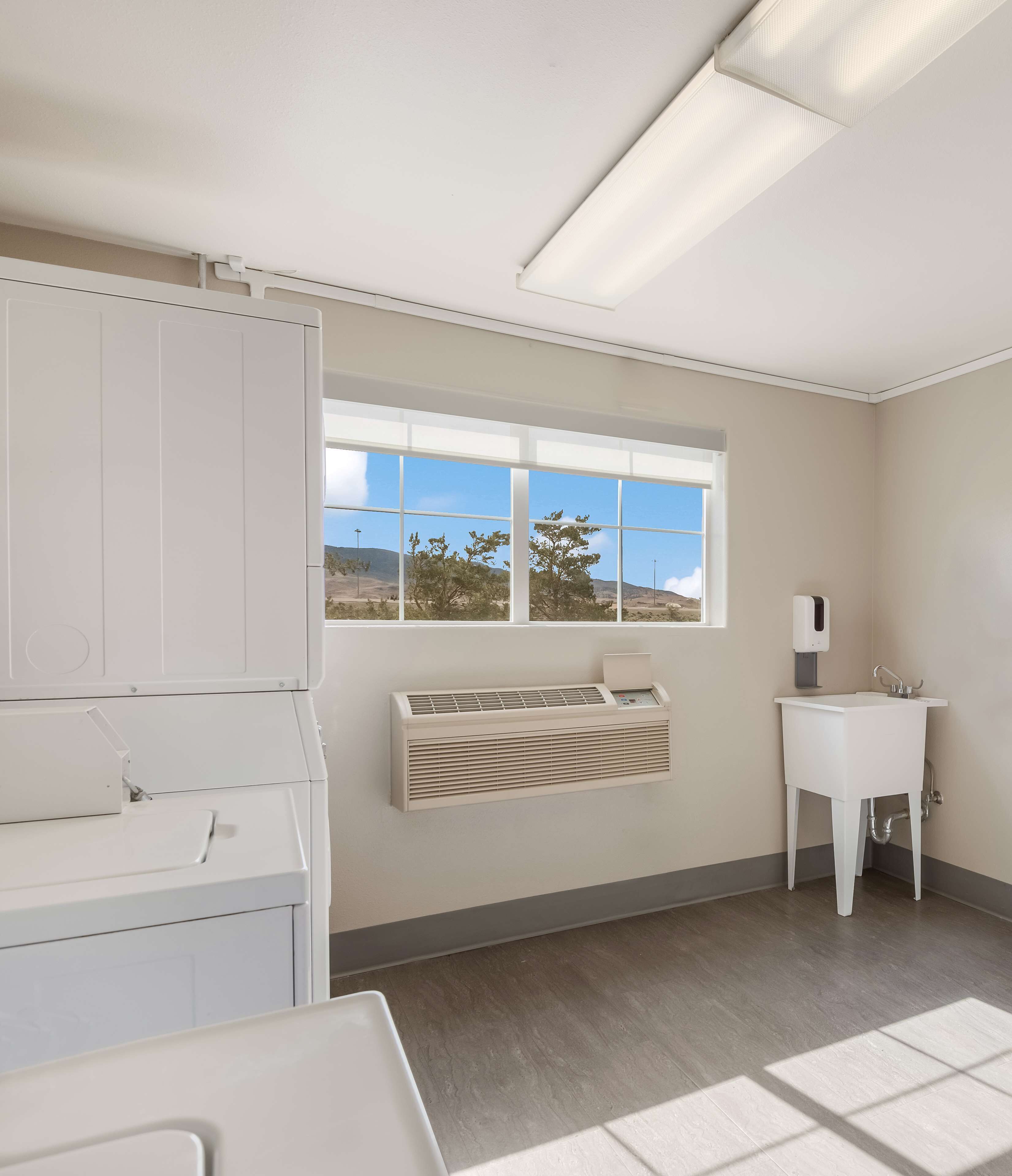 A clean, modern bathroom with a large window, a built-in heater, a sink, and a cabinet.
