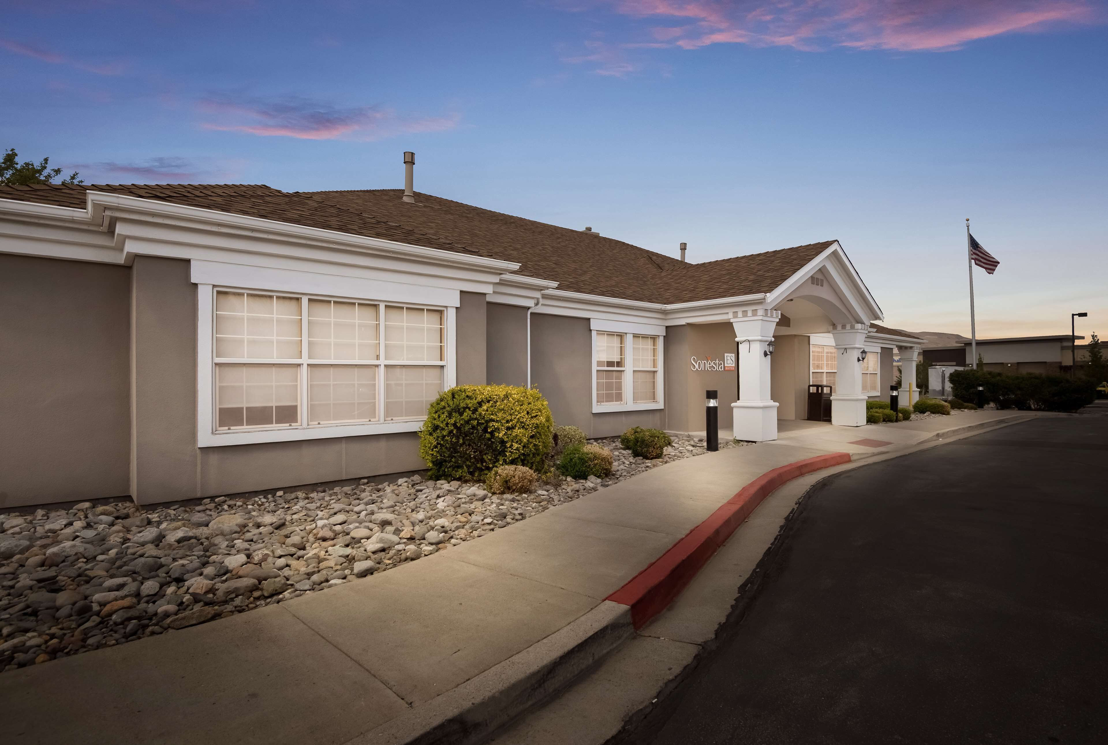 A residential building with a garage, a driveway, and a well-maintained lawn with small bushes.