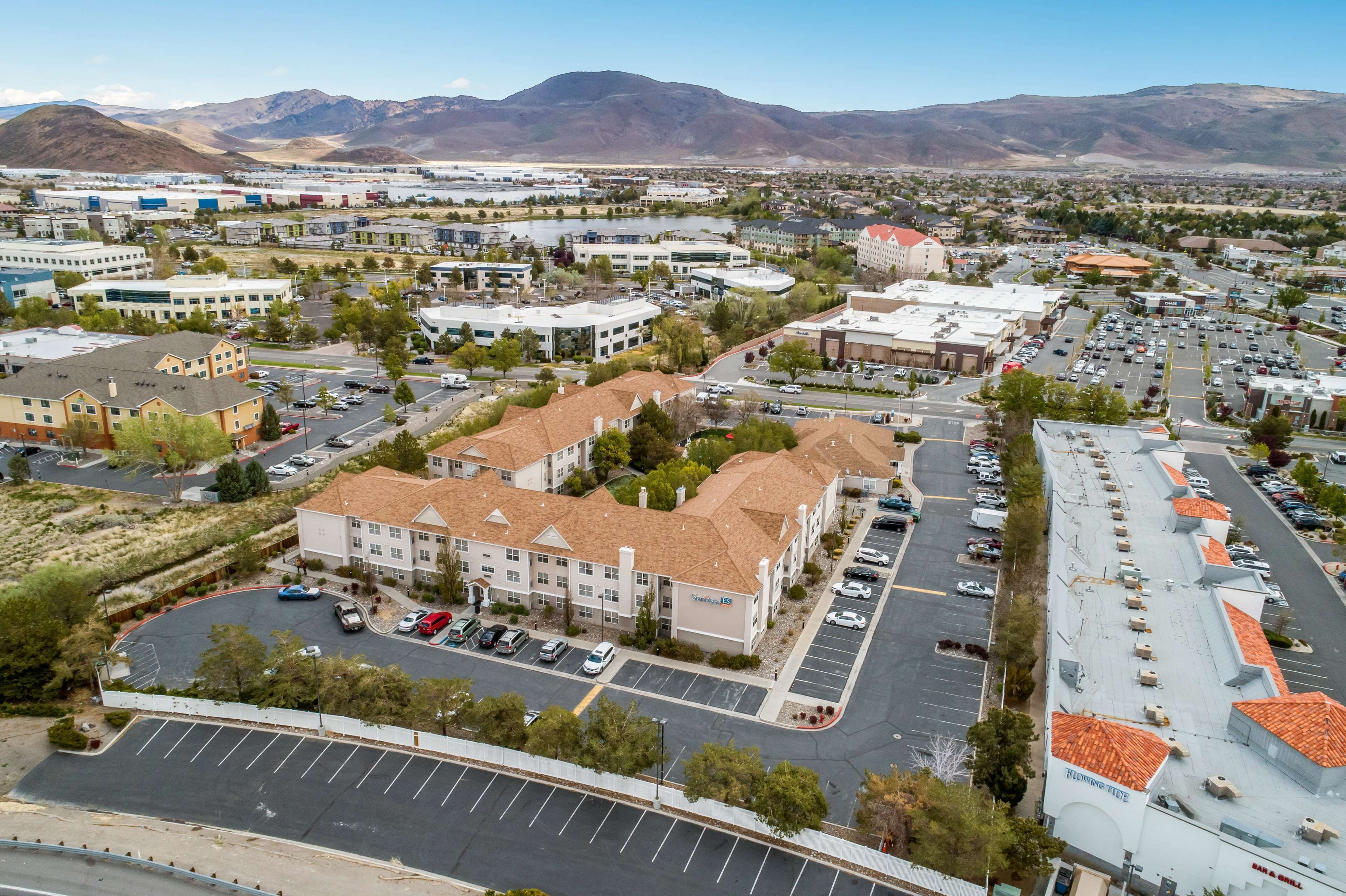 A multi-story hotel with a parking lot, surrounded by mountains and other buildings.