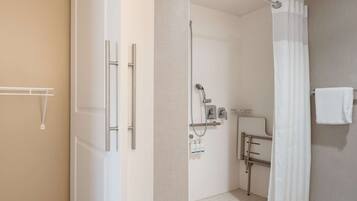 A modern bathroom with a walk-in shower, a toilet with grab bars, and a towel rack.