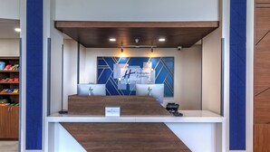 Een modern ogend receptiebalie, met een houten accent en blauwe geometrische wanddecoratie.