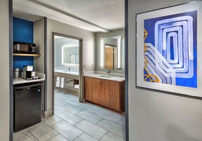 Un baño moderno con lavamanos, espejo y toallero.