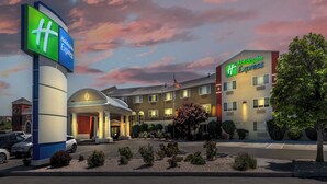 Een Holiday Inn Express hotel met een opvallend bord, een goed verlichte ingang en een parkeerplaats.