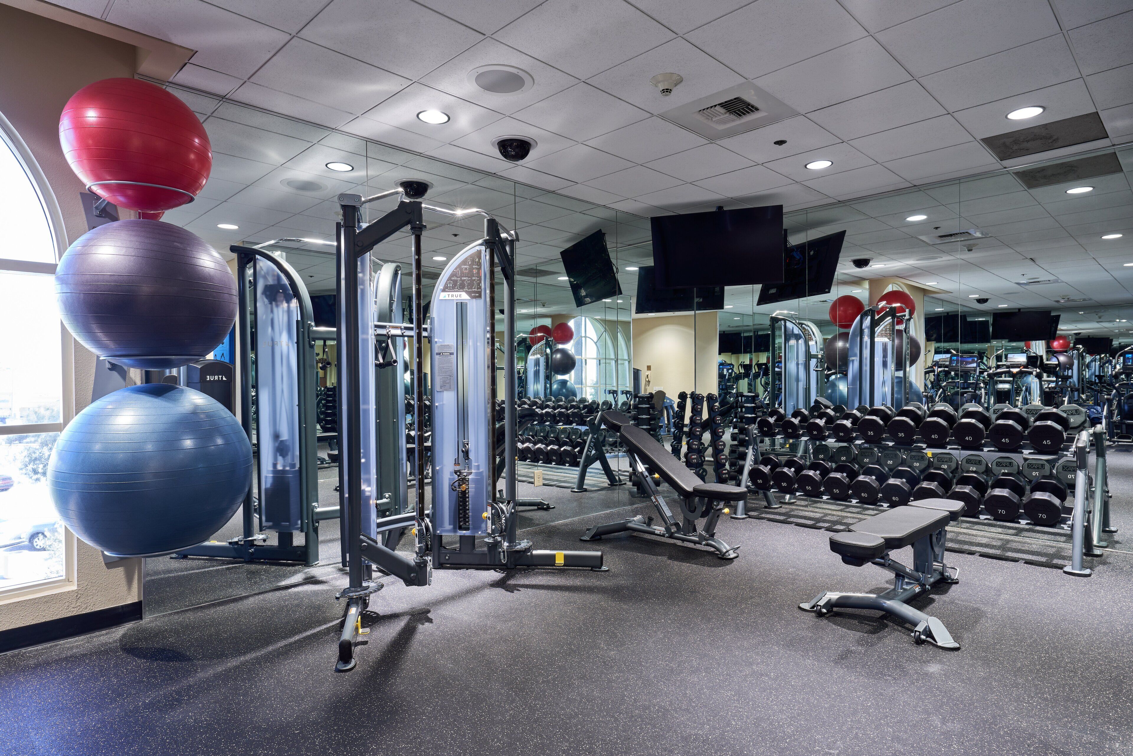 A gym with exercise equipment, weight racks, and a mirror wall.