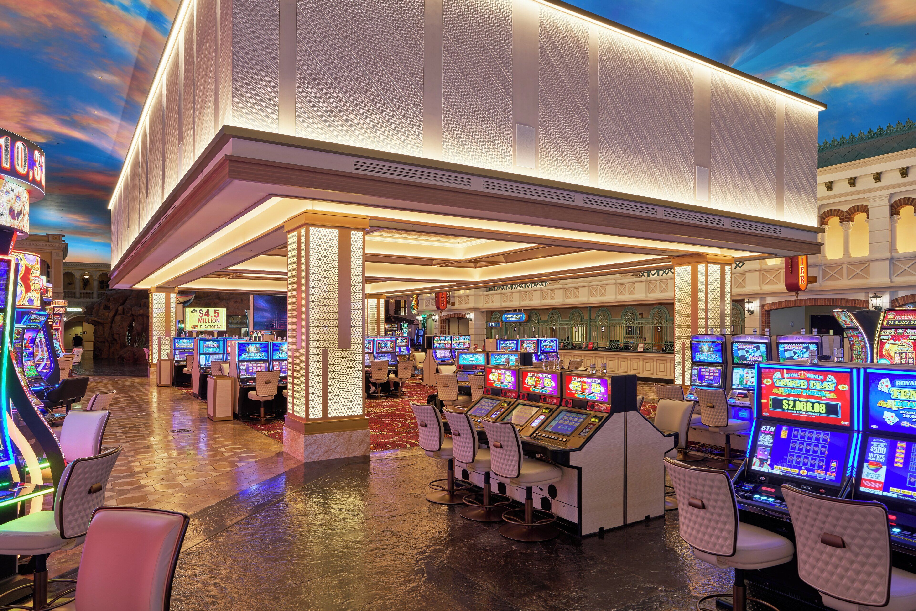 Un casino con numerosas máquinas tragamonedas y un cartel iluminado grande.