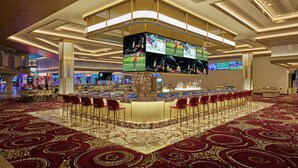 Un hall d’hôtel doté d’un bar, de plusieurs écrans et d’un tapis à motifs.