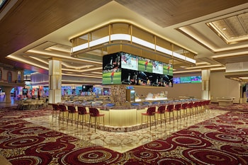 The entrance to Strike Zone Bowling Center with a neon sign, glass doors, and a patterned carpet. at Sunset Station Hotel & Casino