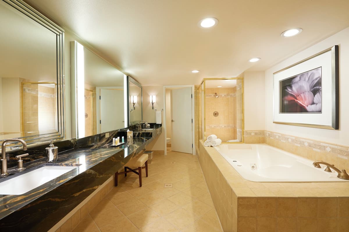 Ein modernes Badezimmer mit großem Spiegel, zwei Waschbecken, einer Badewanne und einer Duschkabine.