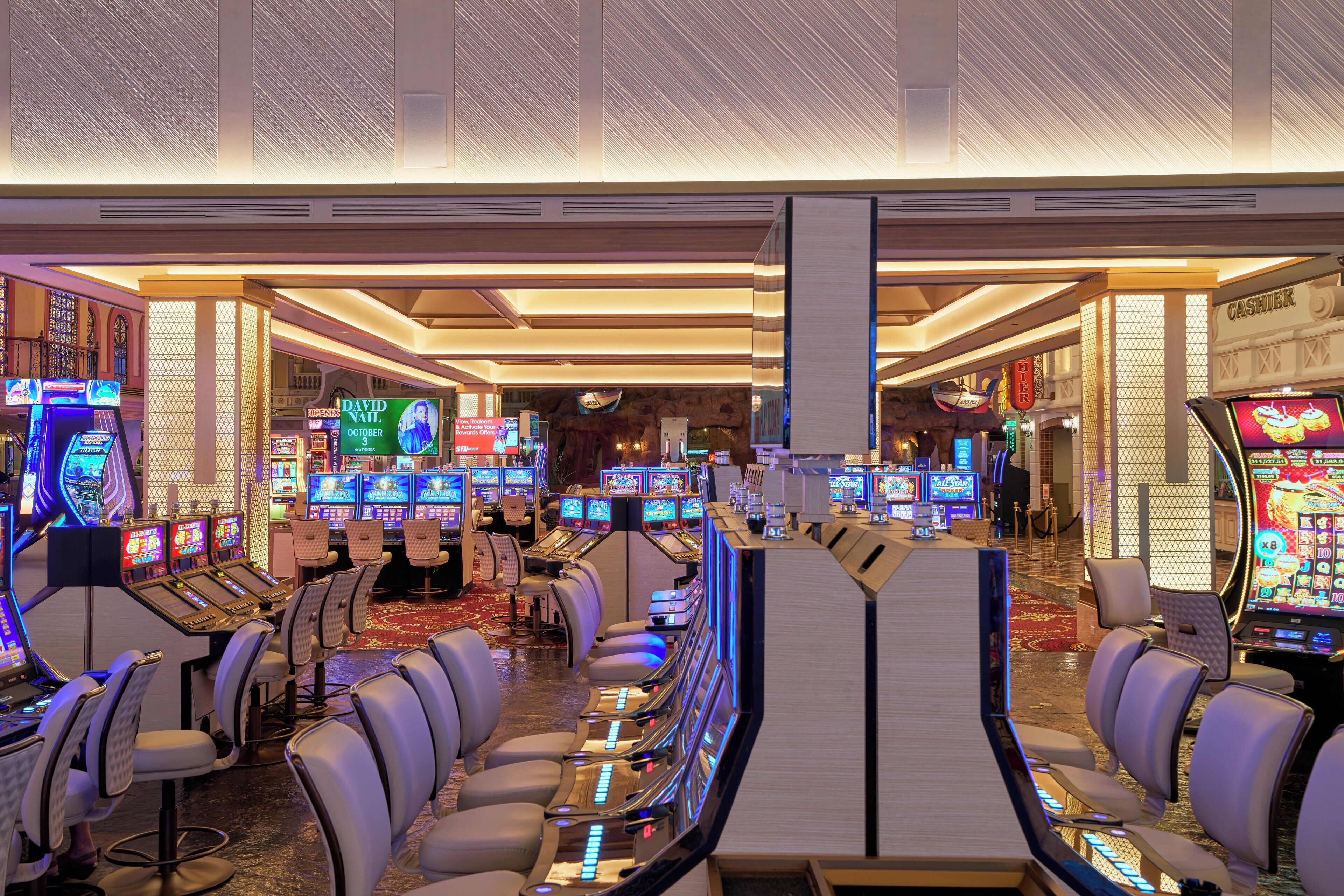 A casino with multiple slot machines, gaming tables, and comfortable seating areas.