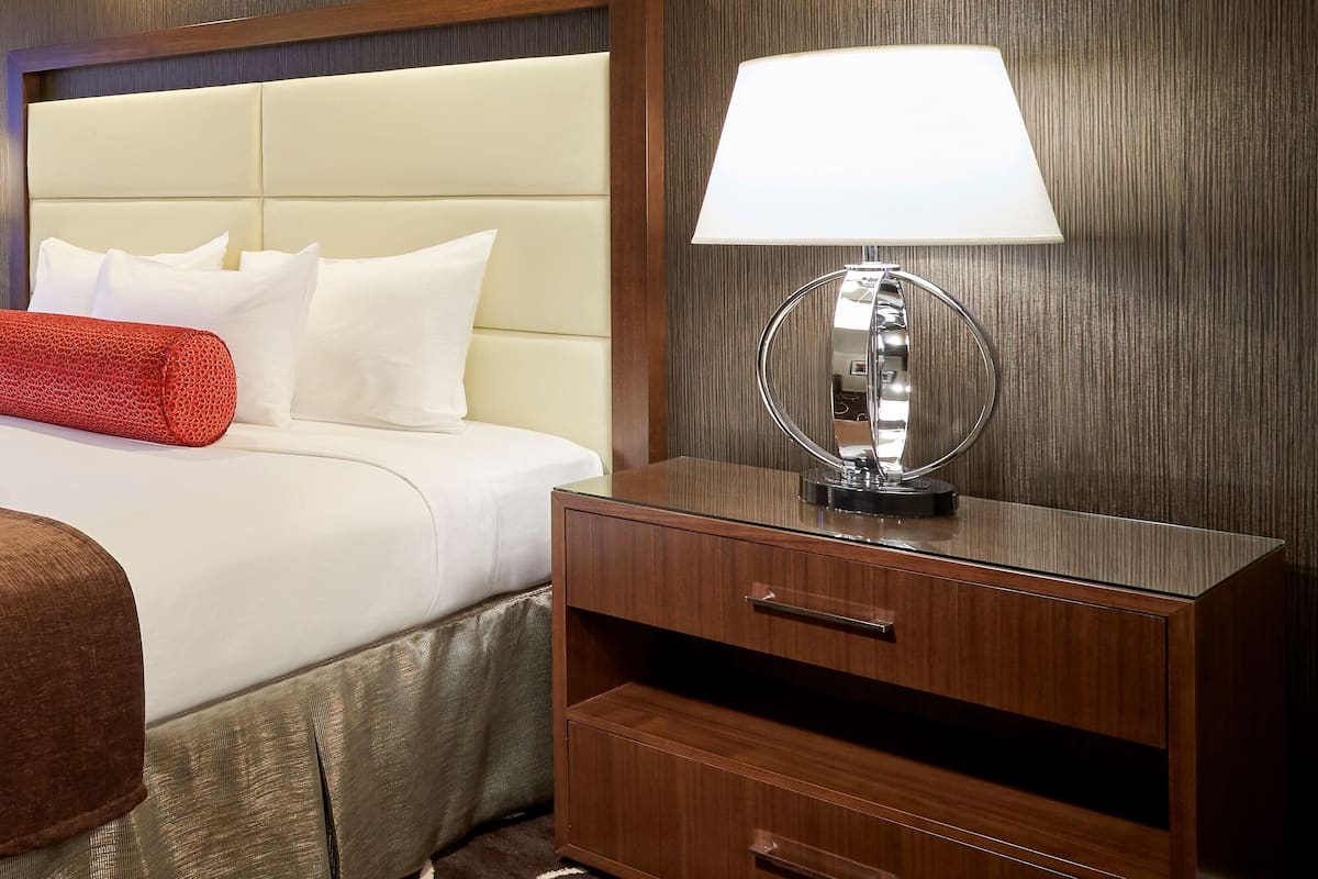 Ein Hotelzimmer mit einem Bett, einer Nachttischlampe und einem Nachttisch mit Schubladen.
