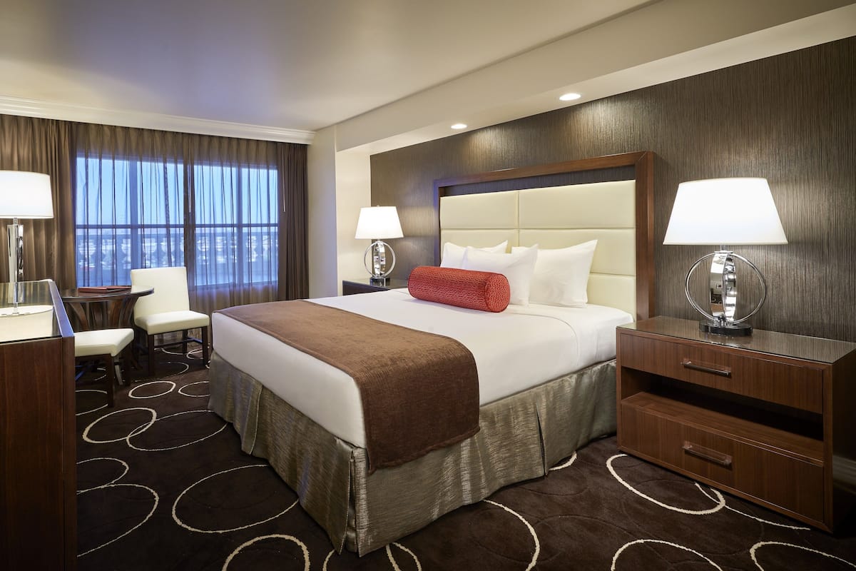 Ein Hotelzimmer mit einem großen Bett, zwei Nachttischen mit Lampen, einem Schreibtisch und einem Stuhl.