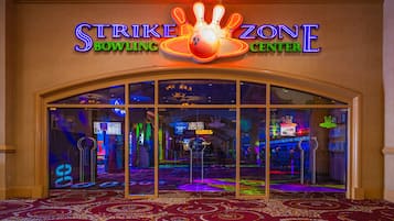 L’entrée du Strike Zone Bowling Center, avec son enseigne au néon, ses portes en verre et son tapis à motifs.