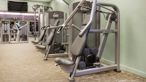 Una palestra con diverse macchine per esercizi, tra cui una pressa per il petto e una pressa per le gambe.