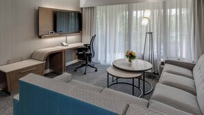 A hotel room with a desk, a sofa, a chair, a TV, and a lamp. - Courtyard by Marriott in Portsmouth (Portsmouth)