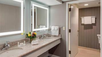 A modern bathroom with two sinks, a large mirror, and a shower area.