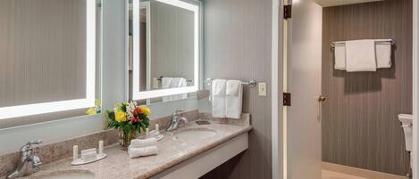 A modern bathroom with two sinks, a large mirror, and a shower area.