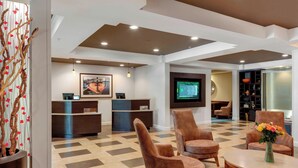 A hotel lobby with a reception desk, seating area, and a television screen. - Courtyard by Marriott in Portsmouth (Portsmouth)