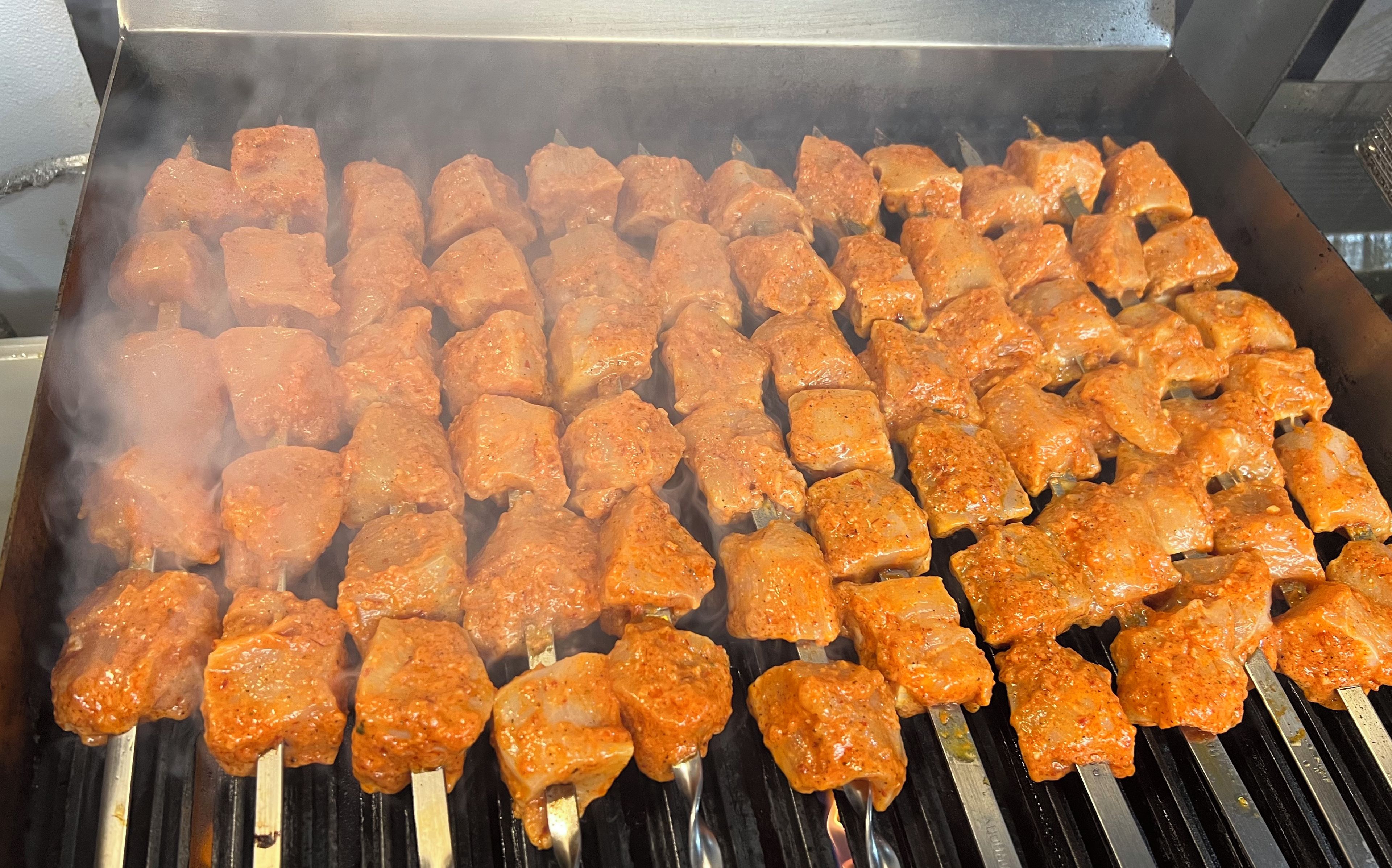 A grill with skewered food items being cooked.