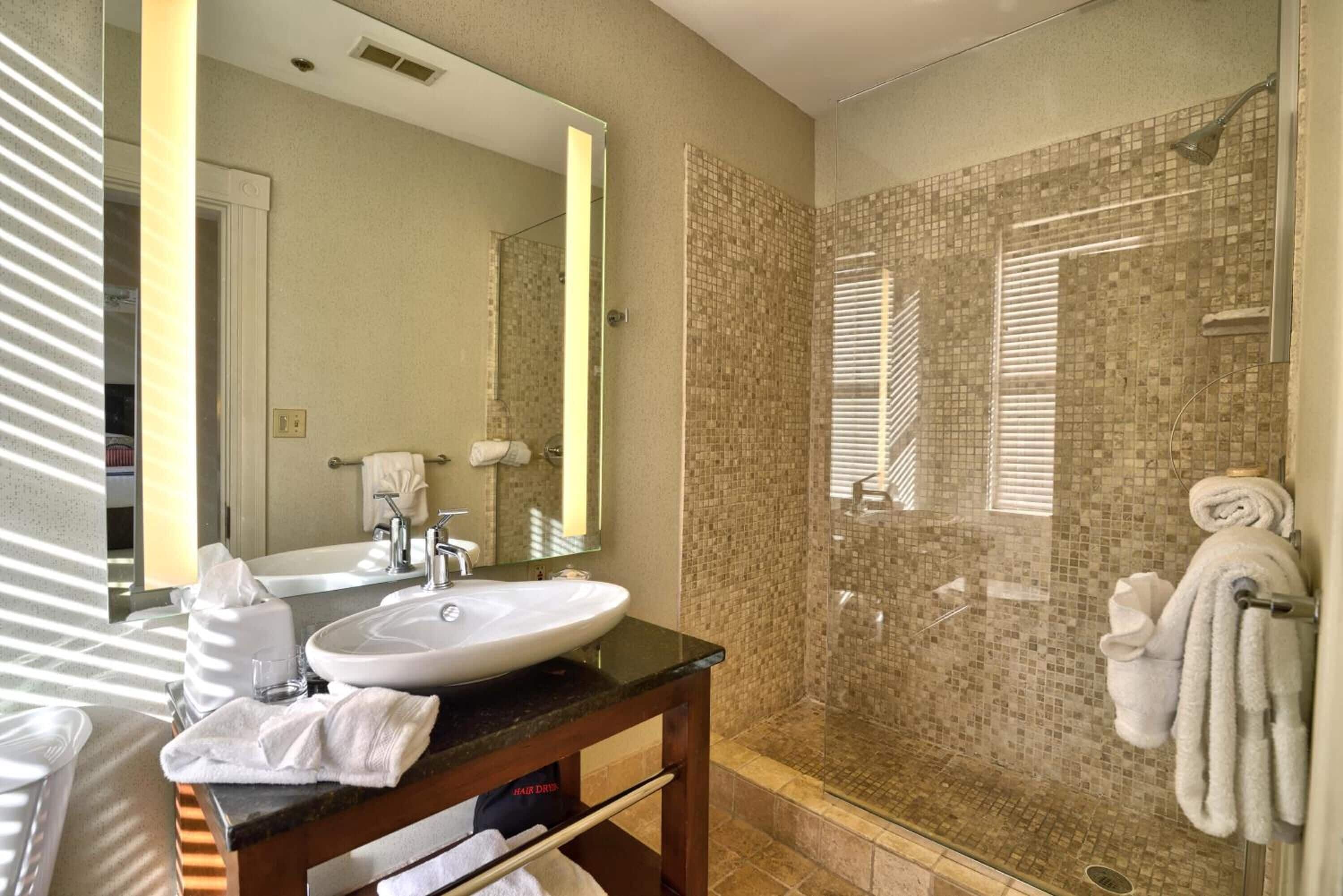 Une salle de bain équipée d’un lavabo, d’un miroir et d’un espace douche.