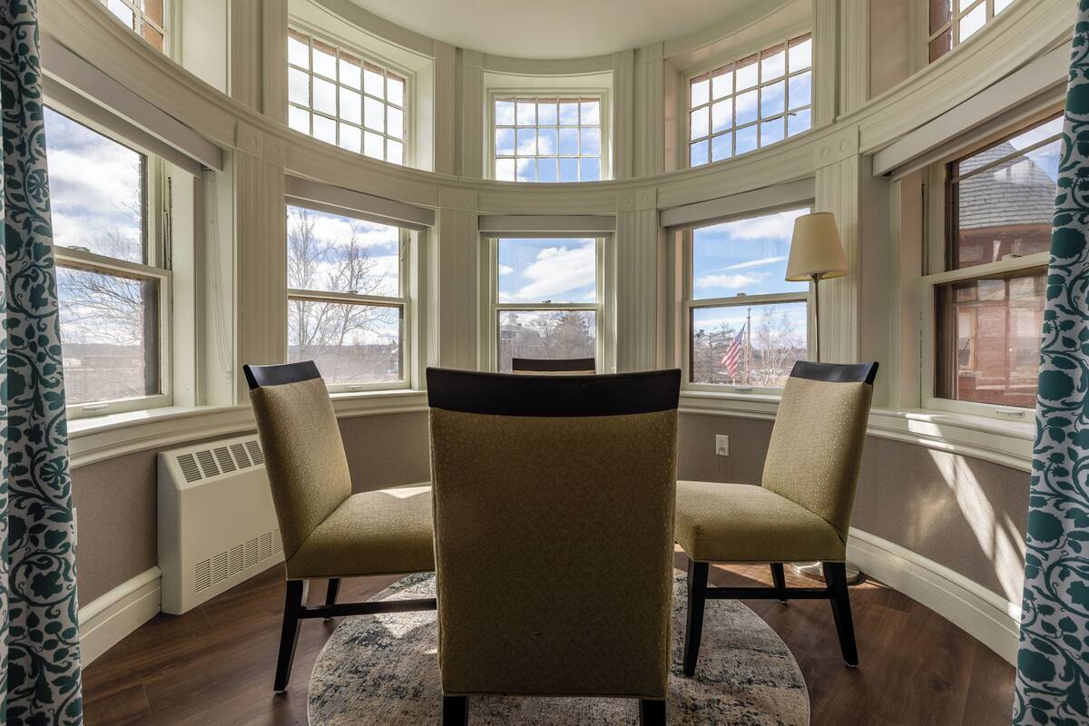 A room with a bay window, two chairs, a lamp, and a radiator.