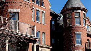 A brick building with two prominent towers, a balcony, and a small porch.