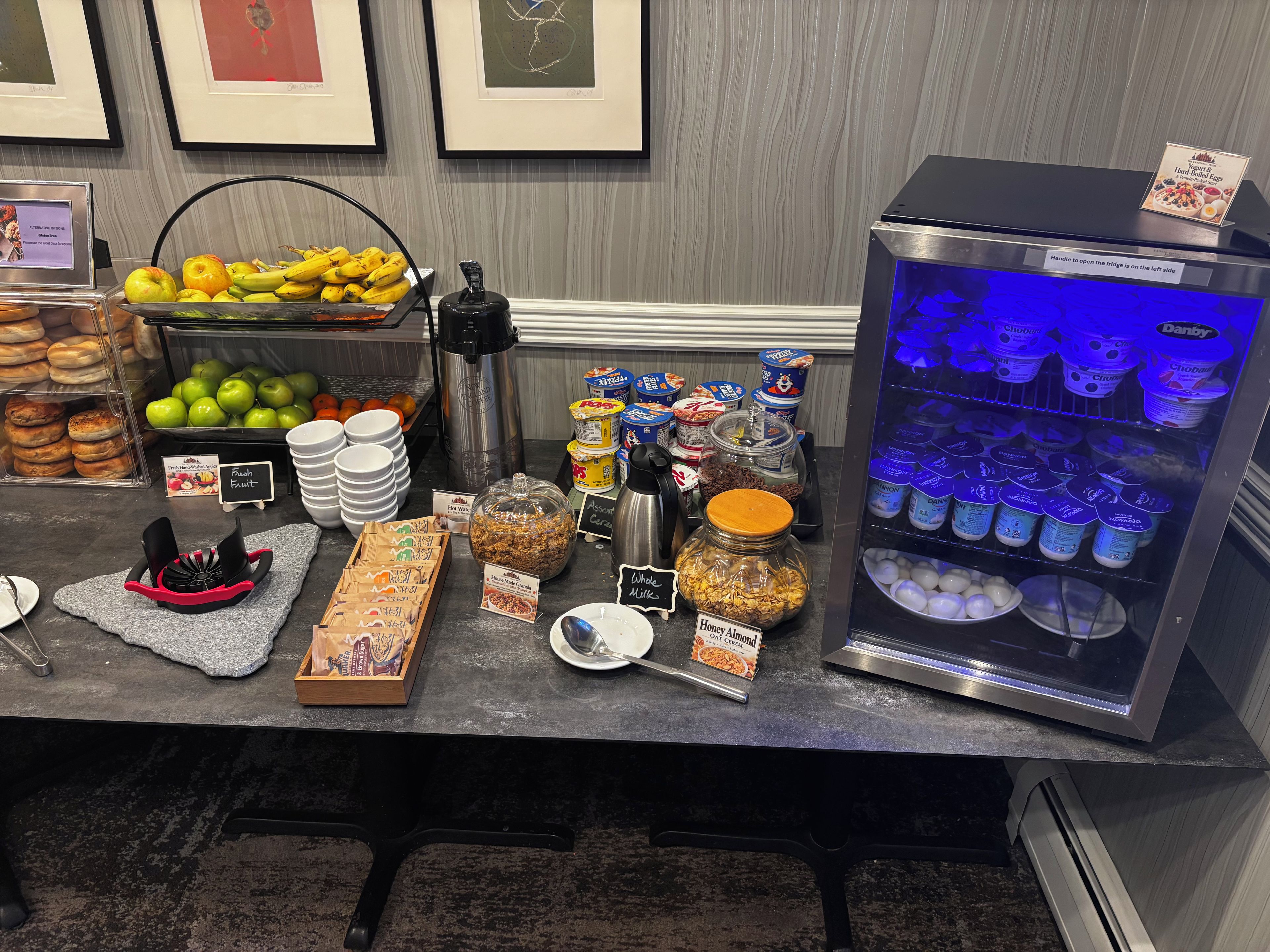 Un bufé de desayuno con diferentes alimentos y un refrigerador lleno de productos lácteos.