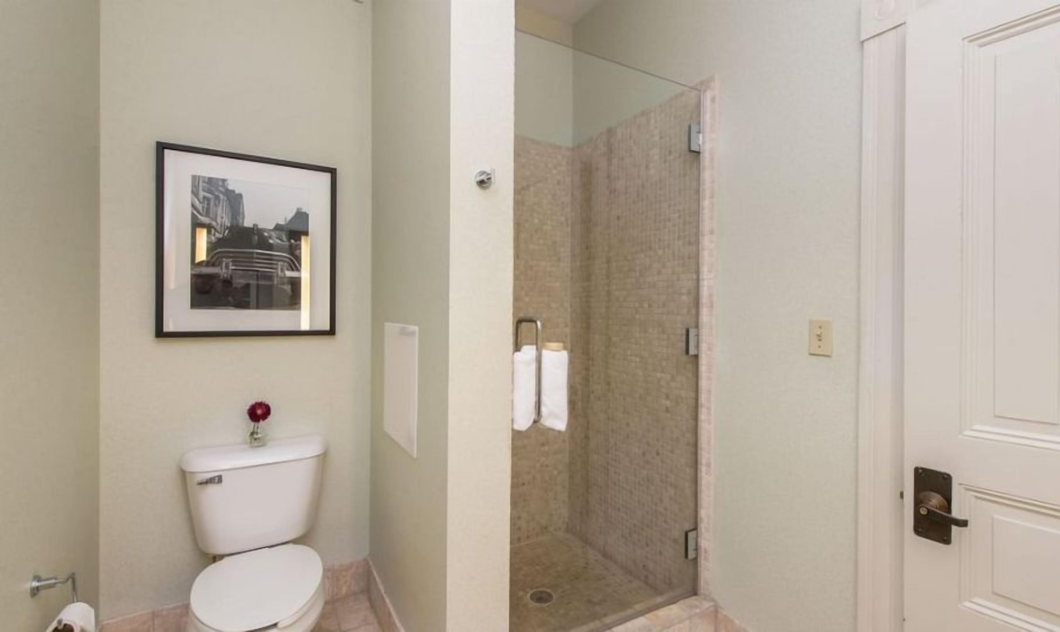 A bathroom with a toilet, a framed picture on the wall, and a shower area.