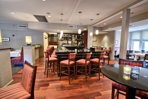 A bar area with a counter, multiple bar stools, and a dining area with a round table and chairs.