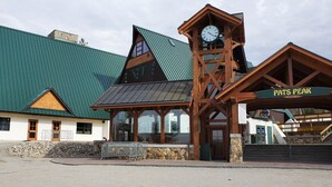 A lodge with a prominent clock tower, a green roof, and a sign reading "Pats Peak". - The Centennial (Concord)