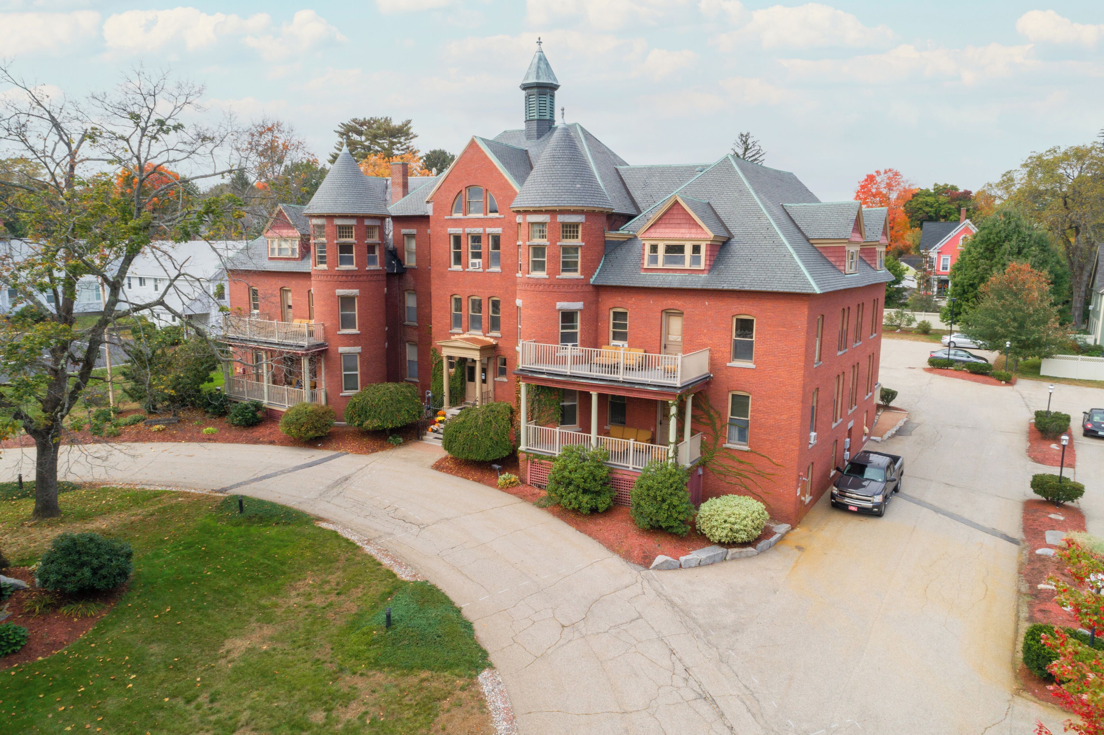 A large brick house with a wrap-around porch and a tower.