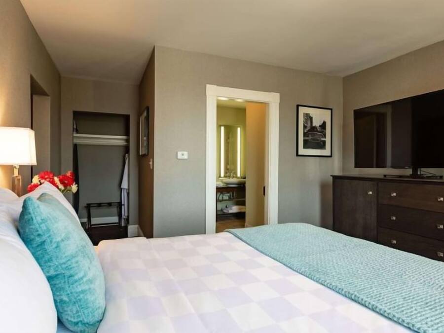 Hotellihuone, jossa on sänky, televisio, lipasto ja vaatekaappi.