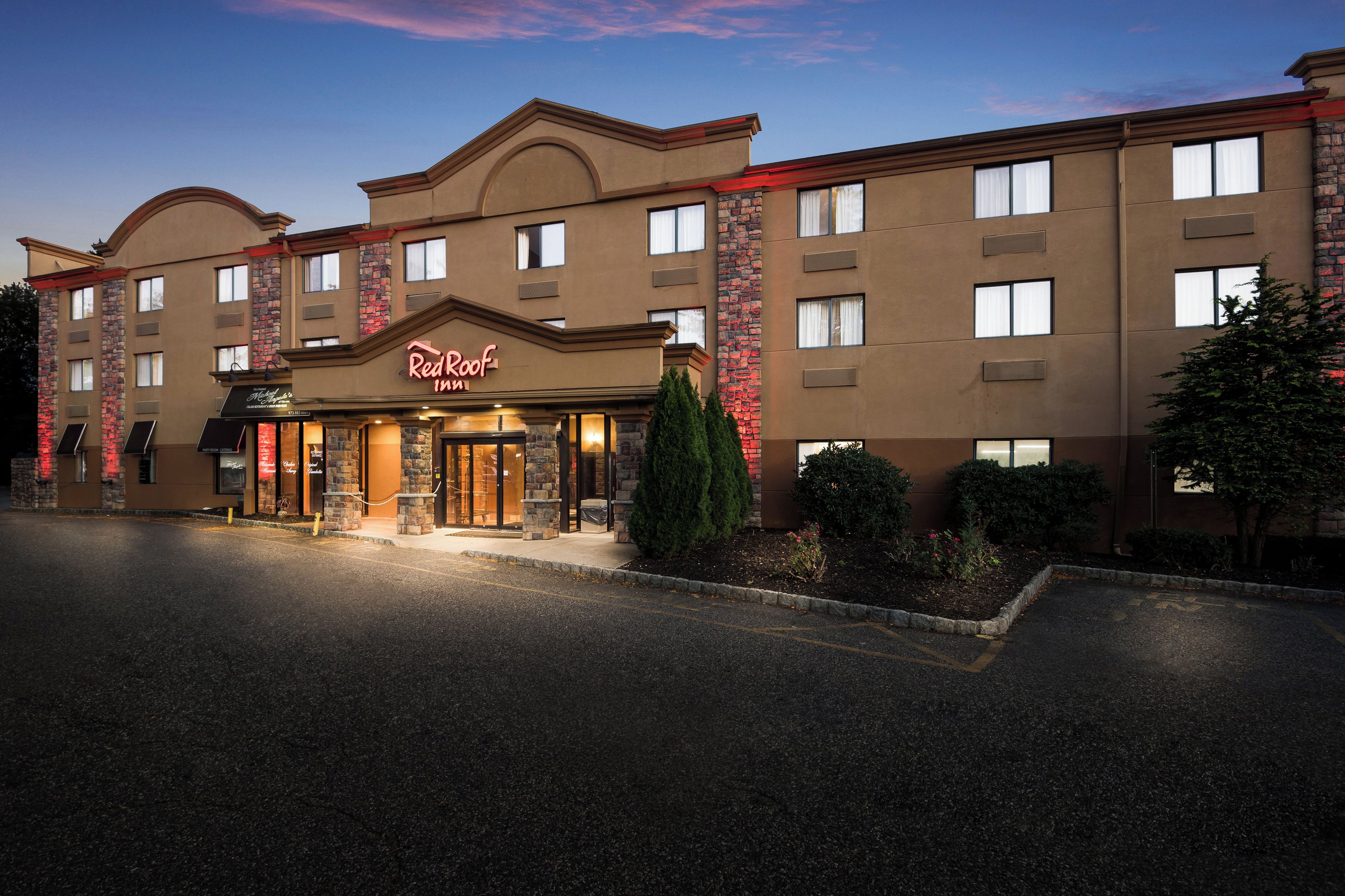 A hotel with a prominent 'Red Roof Inn' sign, multiple windows, and a well-lit entrance.