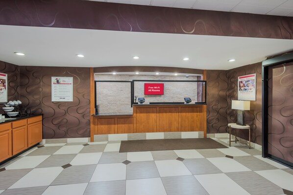 A reception area with a check-in counter, a digital display, and a sign indicating free Wi-Fi availability. - Red Roof Inn Fairfield (Fairfield)