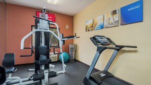 Un gimnasio con equipo de cardio, máquinas de pesas y pelotas de ejercicio.