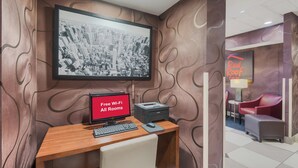 Habitación de hotel con escritorio, computadora y una gran foto de un paisaje urbano en la pared.