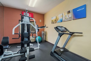 Un gimnasio con equipamiento de ejercicio que incluye una cinta de correr, máquinas de pesas y una bicicleta estática.