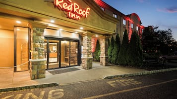 Un Red Roof Inn amb façana de pedra, entrada de vidre i un aparcament amb un rètol que diu 'PARKING'.