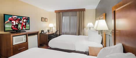 Una habitación de hotel con una cama, un escritorio con televisor, un microondas y dos lámparas.