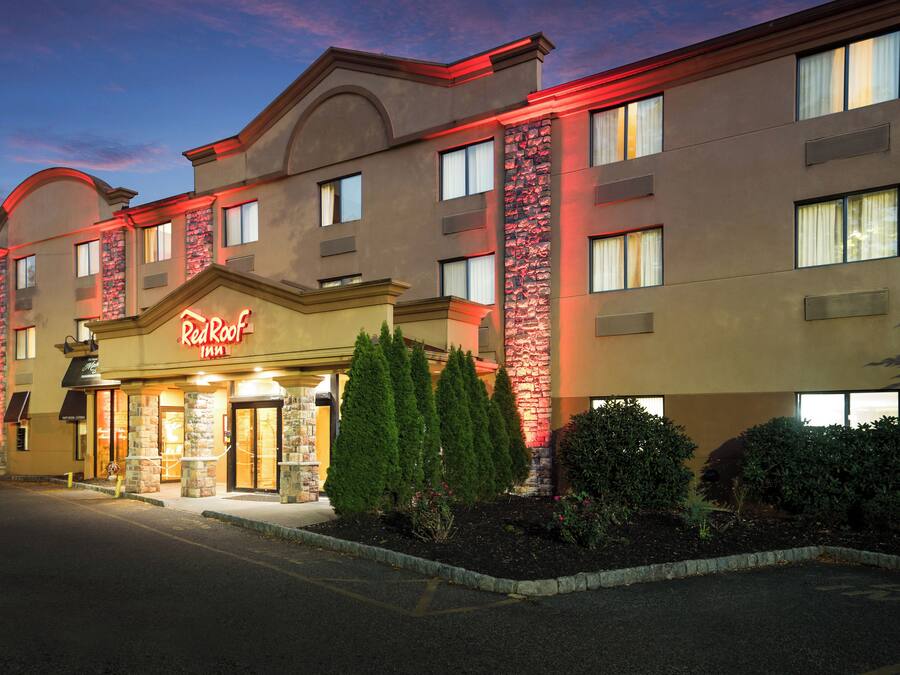 A hotel with a prominent sign, multiple windows, and a landscaped front yard.